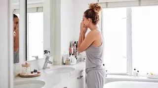 Kobieta przeglądająca się w lustrze, zatykająca nos