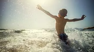 Chłopiec korzystający z uroków kąpieli w morzu.