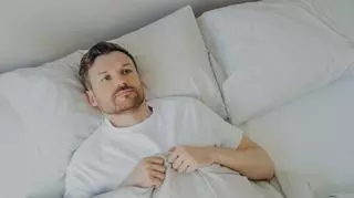 Mężczyzna w łóżku bojący się zasnąć