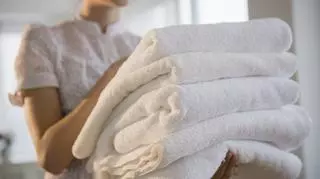 Złożone w kostkę białe ręczniki w kobiecych dłoniach.