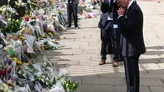 Król Karol III ogląda kwiaty zostawione przed Pałacem Buckingham