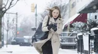 Kobieta w płaszczu, która idzie przez zaśnieżoną ulicę 