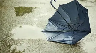 Połamana parasolka leżąca obok kałuży