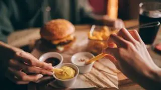 Dwie osoby jedzące hamburgera i frytki