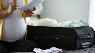 Kobieta w ciąży z walizką