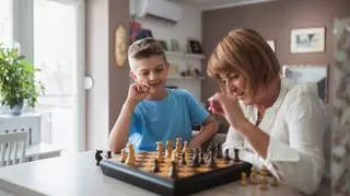 Dorosła osoba grająca z dzieckiem w szachy