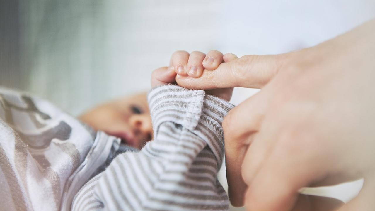 Matka trzyma małe dziecko, niemowlę, za rękę. Dłonie.