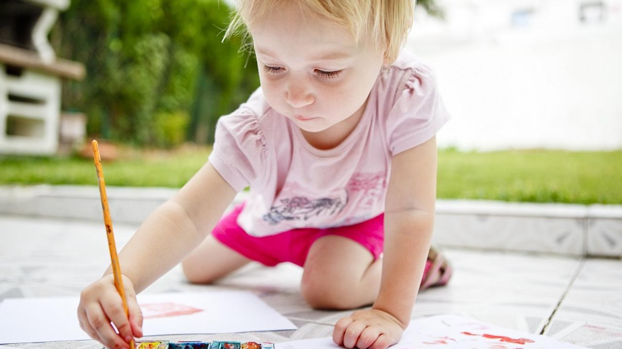 Dziecko rysuje farbami na kartonie.