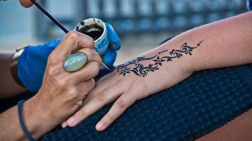 Kobieta, która ma robiony tatuaż z henny na dłoni 
