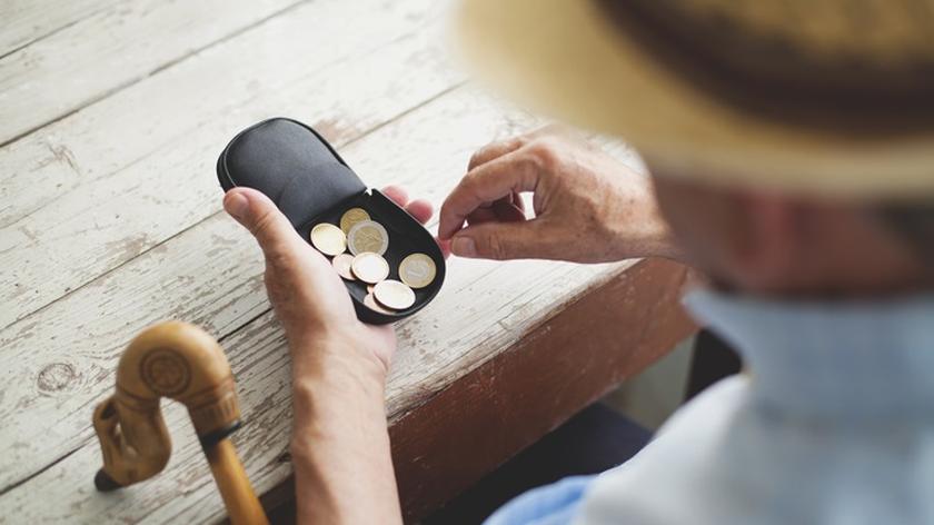 Starszy pan liczy drobne w portfelu 
