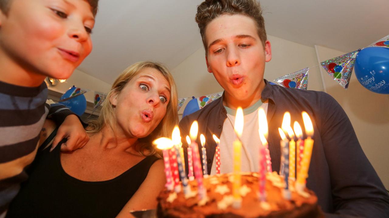 18-letni chłopak zdmuchuje świeczki na urodzinowym torcie