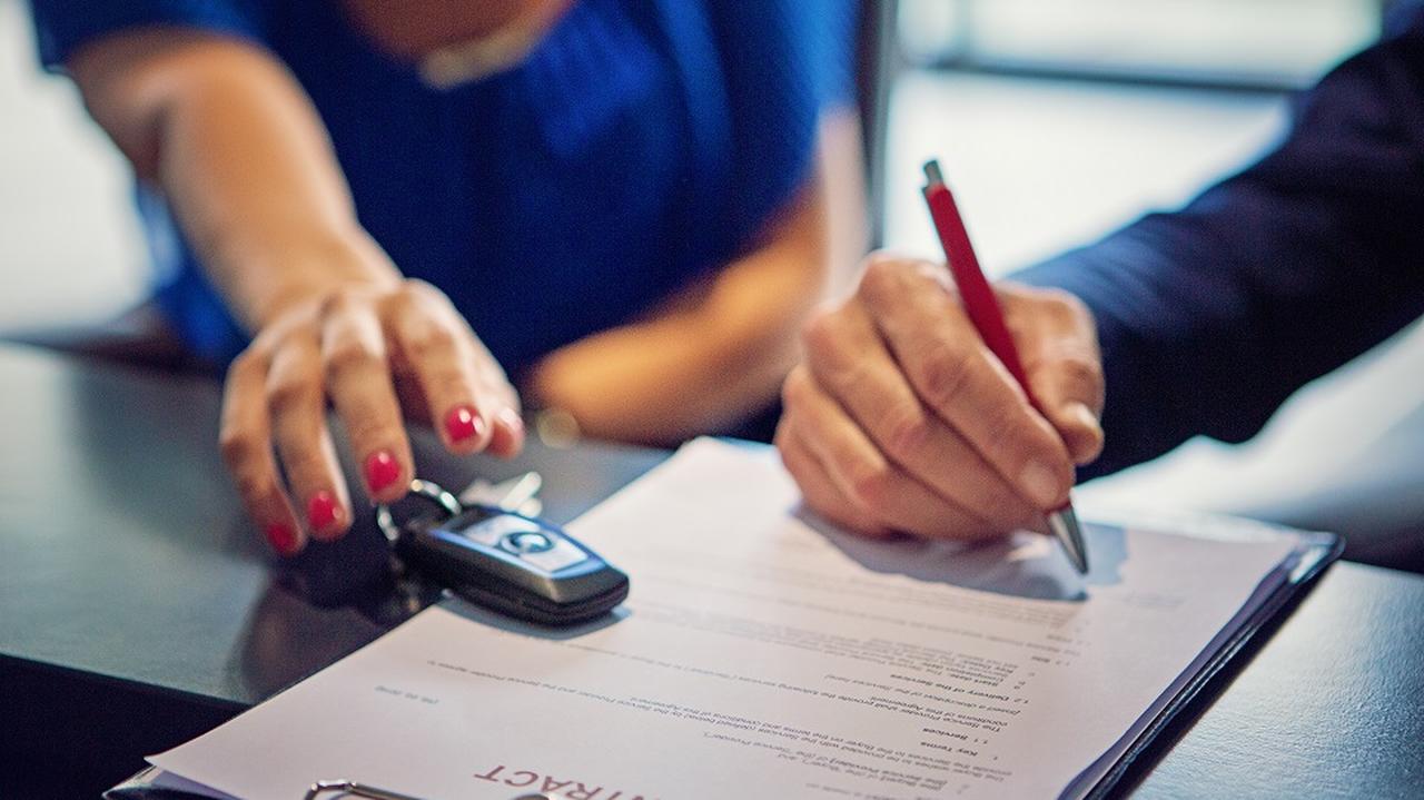 Mężczyzna i kobieta podpisują umowę na leasing samochodu.