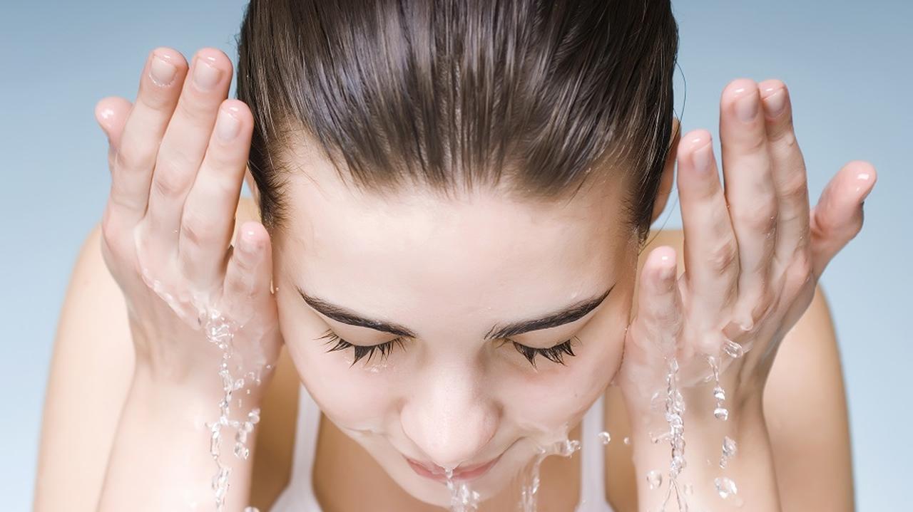 Kobieta myje twarz wodą