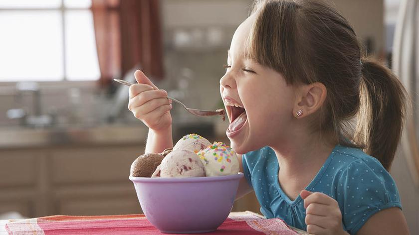 Dziewczynka je lody z miseczki. 