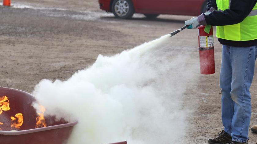 Strażak w trakcie pracy - gasi pożar za pomocą gaśnicy.