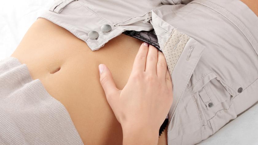 Kobieta wkłada sobie rękę w spodnie.