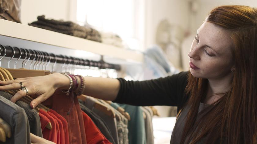 Kobieta w sklepie odzieżowym wybiera ubrania