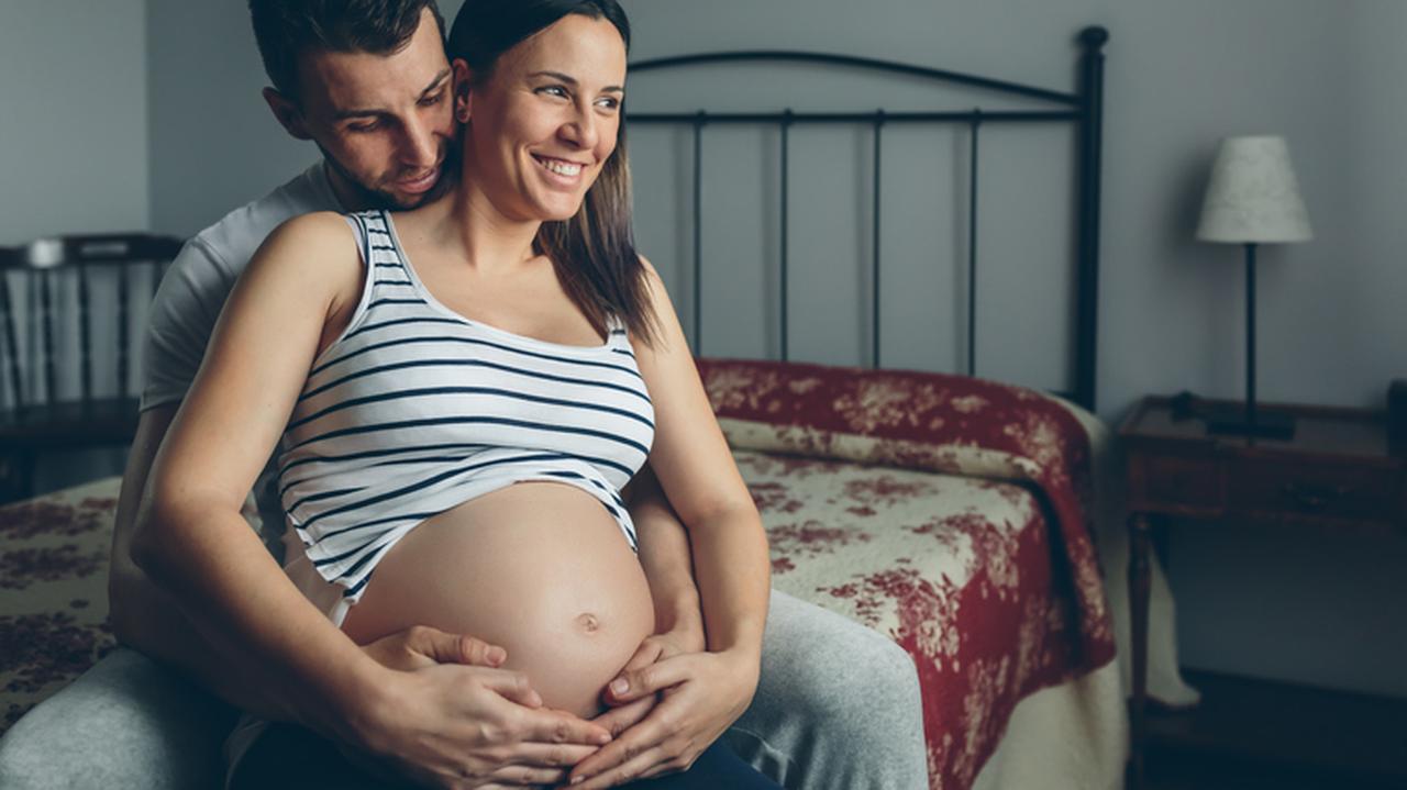 Mężczyzna przytula kobietę w ciąży