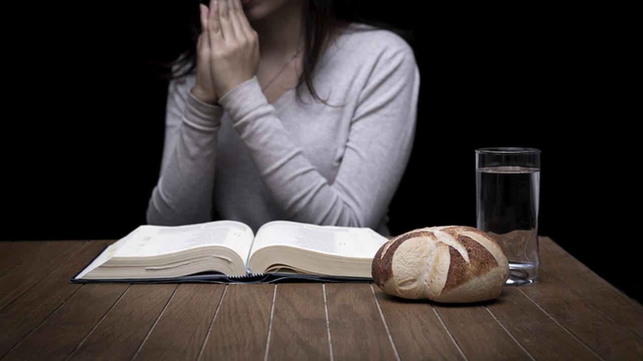 Kobieta się modli, z książką, wodą, chlebem