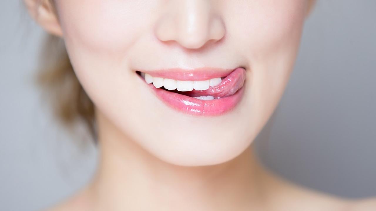 uśmiechnięta kobieta pokazuje białe zęby i figlarnie wystawia język