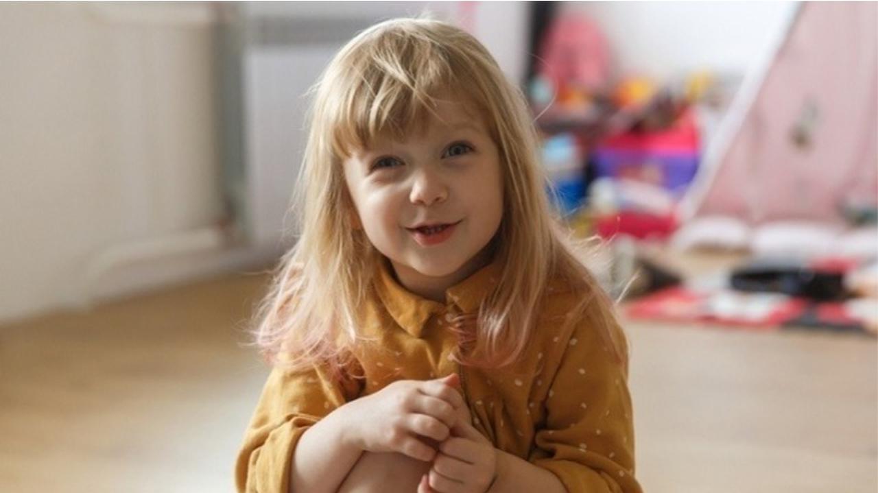 Uśmiechnięta mała dziewczynka, siedząca na podłodze
