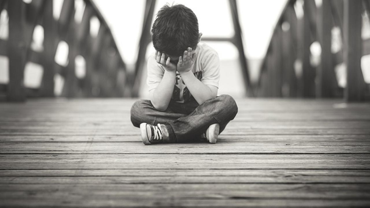 smutne dziecko siedzi na moście, zdjęcie czarno białe