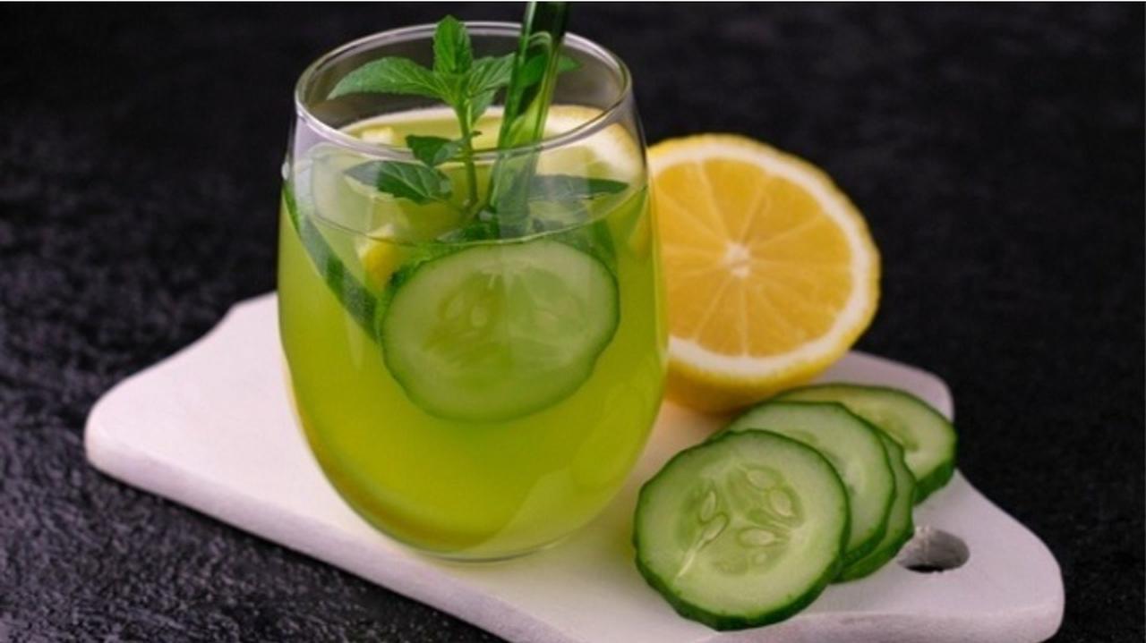 Szklanka z zielonym napojem, otoczona plasterkami ogórka