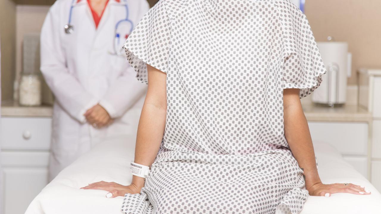 Kobieta w koszuli do badania podczas wizyty u ginekologa