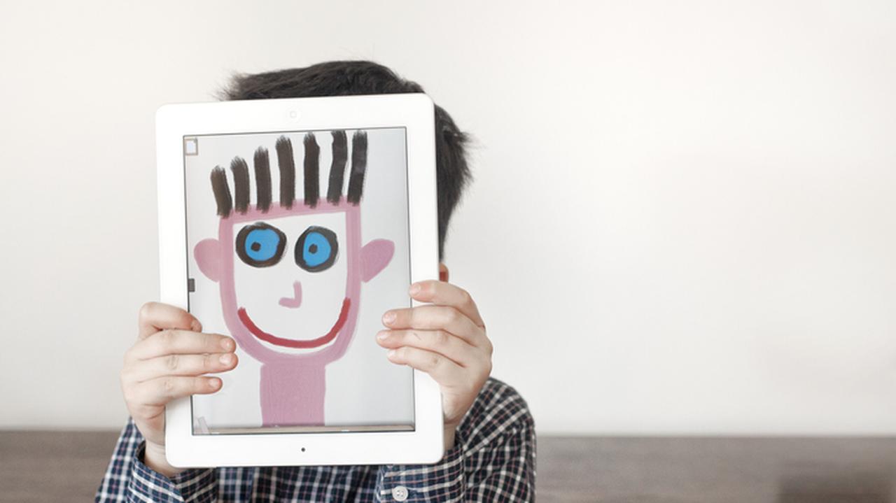 Dziecko trzyma obrazek z namalowaną twarzą