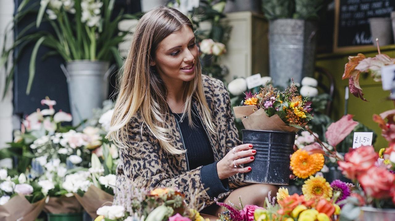 Kobieta w kwiaciarni wybiera bukiet kwiatów. 