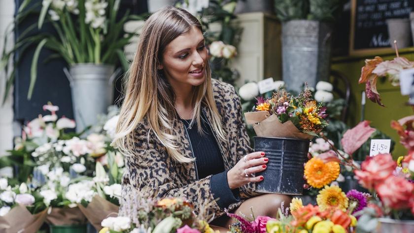 Kobieta w kwiaciarni wybiera bukiet kwiatów. 