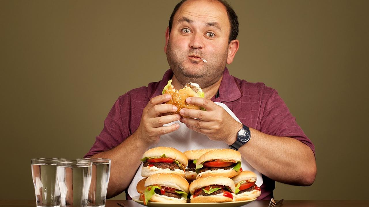 Otyły mężczyzna je tłuste hamburgery 