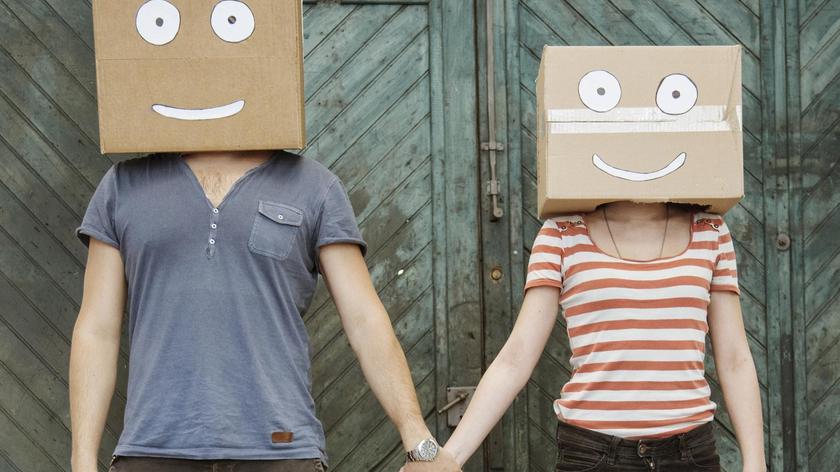 Para trzymająca się za ręce z zabawnymi kartonami na głowie 