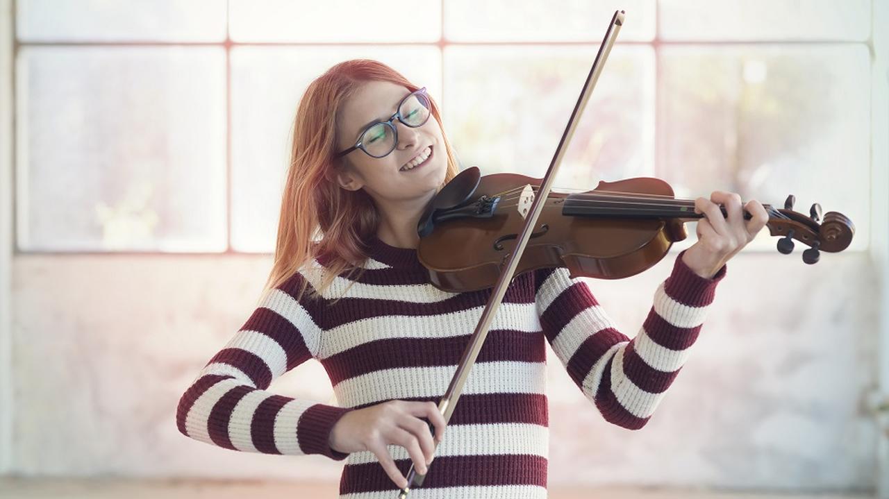 Rudowłosa dziewczyna gra na skrzypcach