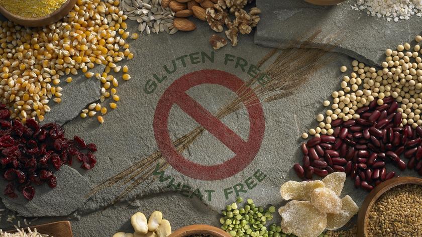 Napis na betonie: gluten free, dookoła rozsypane ziarna kukurydzy, fasoli