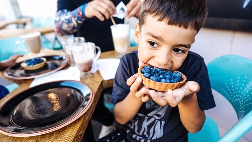 Desery dla dzieci, chłopiec je zdrowe ciastko z jagodami