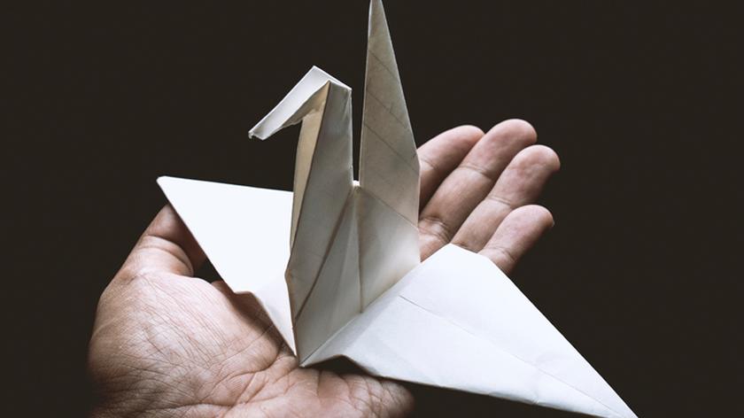 Żuraw origami na męskiej dłoni