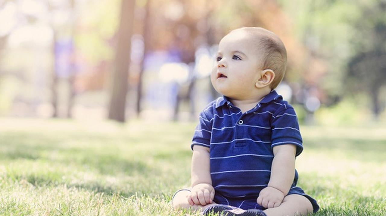 małe dziecko siedzi na trawie