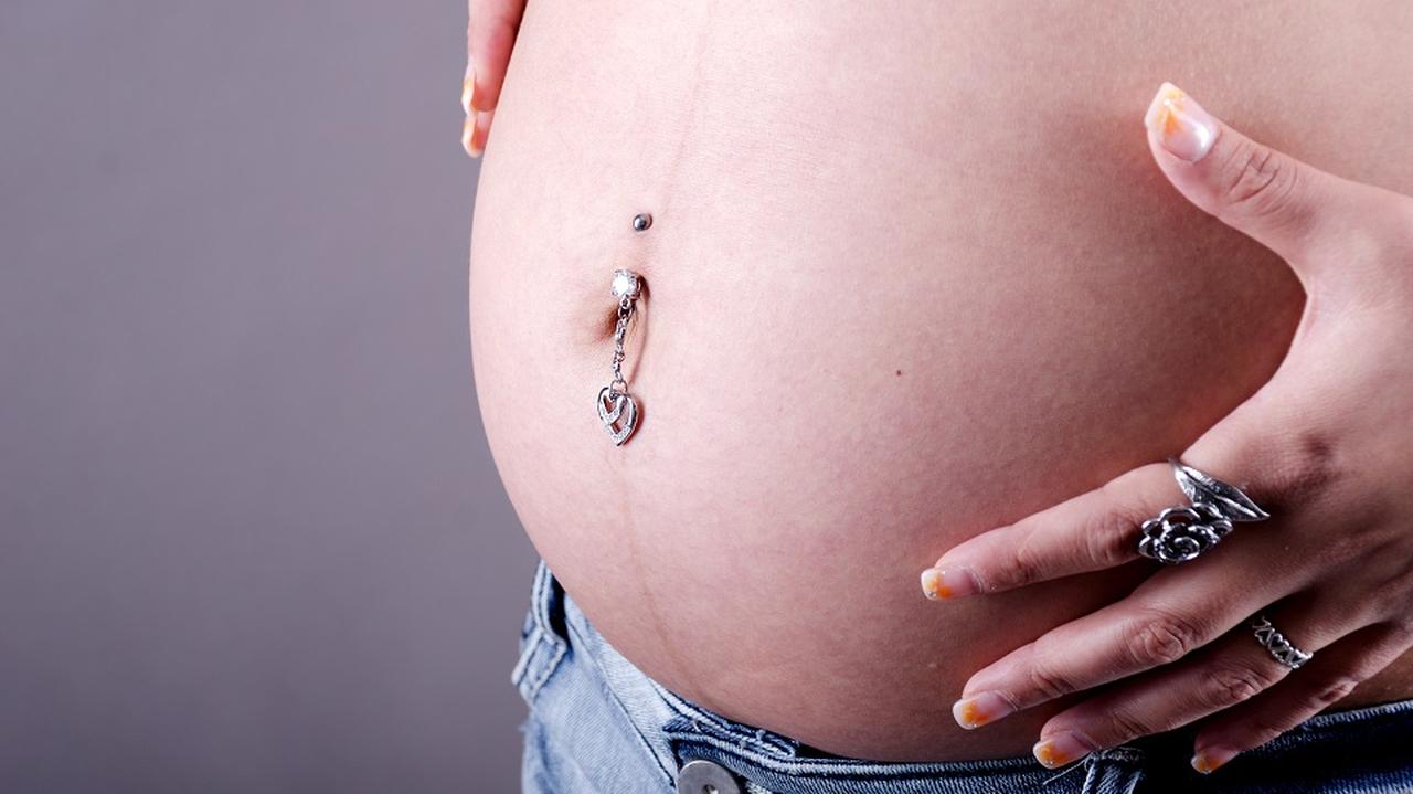 Kobieta w ciąży, która ma kolczyk w pępku 