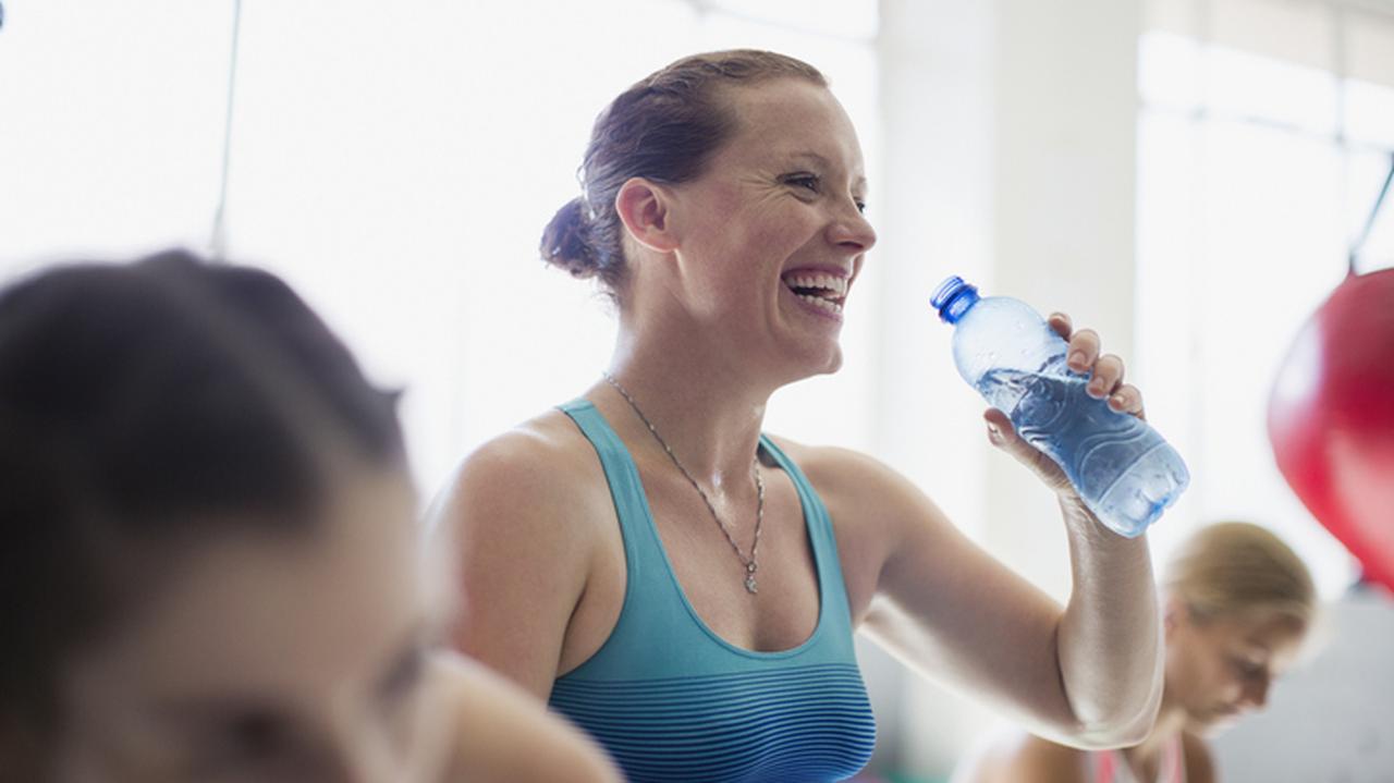 Kobieta na treningu pije wodę