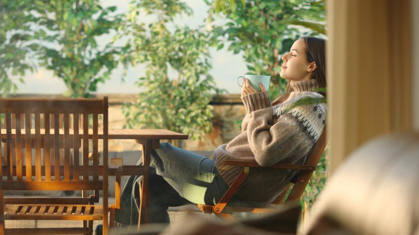 Kobieta na tarasie, z zamkniętymi oczami, głęboko oddychająca