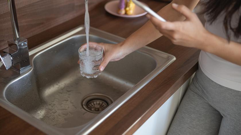 Kobieta nalewająca wodę z kranu do szklanki