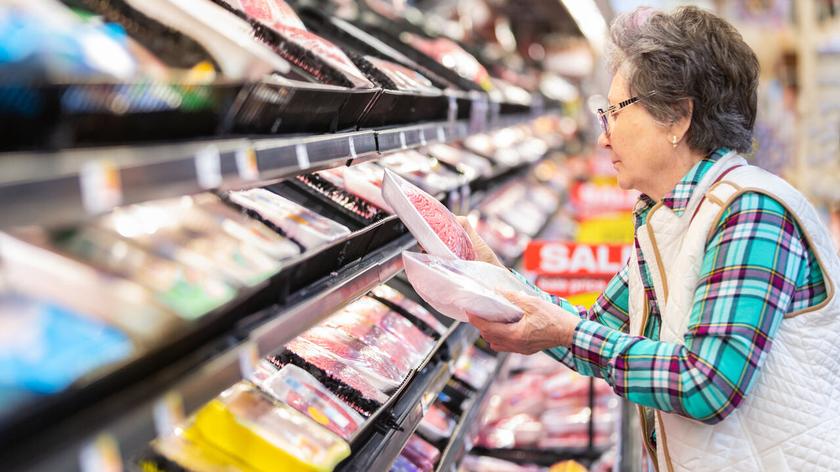 starsza kobieta w sklepie ogląda produkty w dziale z mięsem