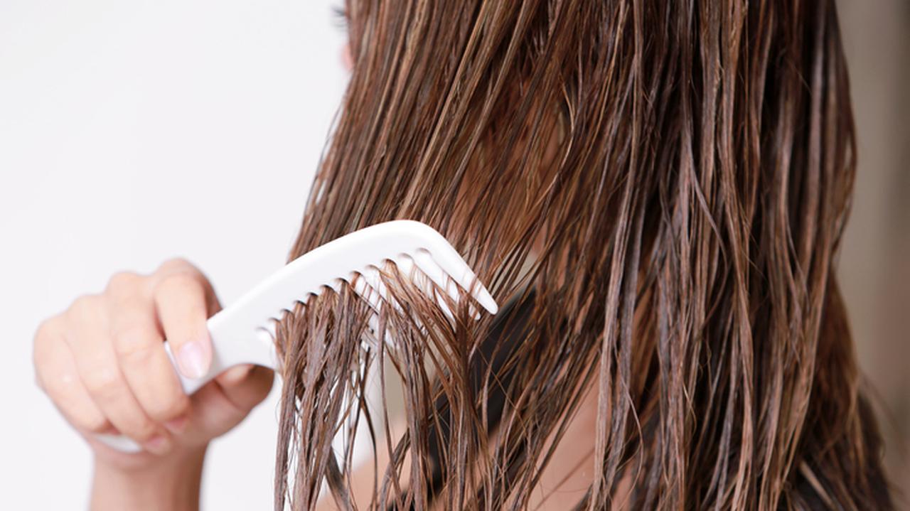 Kobieta rozczesująca mokre włosy. Pielęgnacja włosów. Woda lamelarna do włosów.