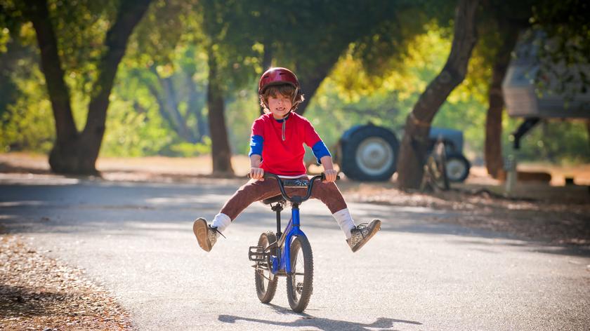 dziecko na rowerze jeździ w parku, rower dla dziecka, sportowa stylizacja dla dziecka, kask na rower