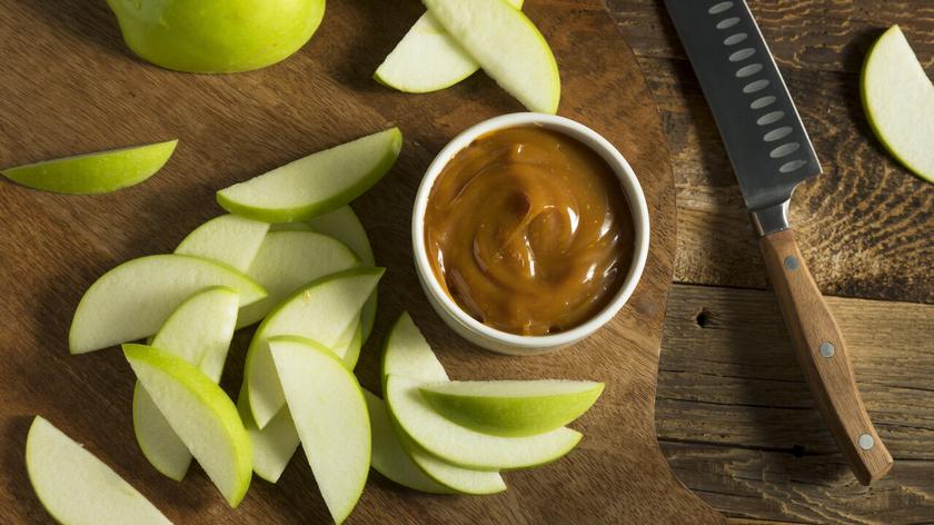 Jabłka pokrojone w cząstki i karmel w miseczce