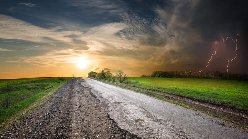 Błyskawice i słońce na niebie nad drogą