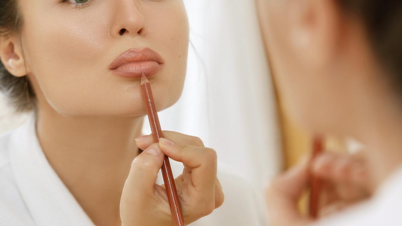 Kobieta malująca usta konturówką. Makijaż ust. Powiększanie ust makijażem. Triki makijażowe.