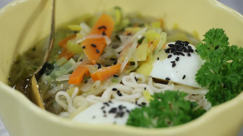 "Ramen" drobiowo-warzywny, serwowany z marynowanymi jajkami w sosie sojowym, podany z czarnym sezamem, imbirem i maślanymi nudlami