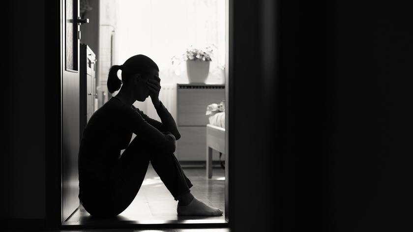 Kobieta siedząca w pokoju w ciemności